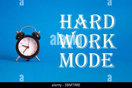 Simbolo della modalità di lavoro duro. Concetto di modalità lavoro duro su sfondo blu con sveglia. Concetto di modalità Business e Hard Work. Copia spazio Foto Stock