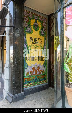 Un vivace shopping in stile Art Nouveau con colorate piastrelle che pubblicizzano "KOKES & CONFECTIONS", che riflettono il fascino vintage e la pubblicità artistica di strada Foto Stock
