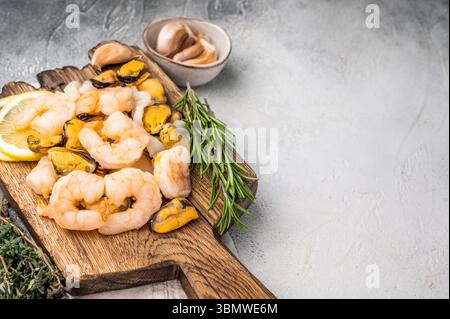 Cocktail di pesce fresco, miscela cruda con cozze, vongole, gamberi, gamberi e calamari su tavola di legno. sfondo bianco. vista dall'alto. Foto Stock