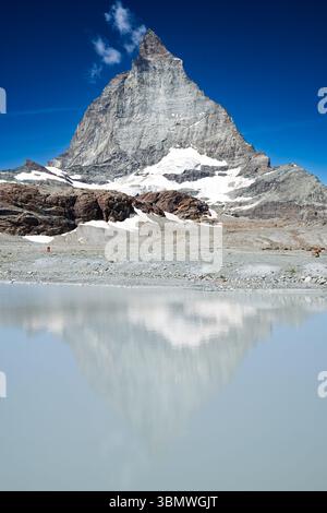 L'iconica montagna Cervino si riflette in un tranquillo lago alpino in una giornata limpida. Foto Stock