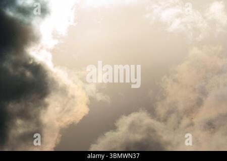 Le nuvole spesse riempiono il cielo mentre la luce del sole attraversa, proiettando un bagliore drammatico in una scena d'atmosfera soffusa Foto Stock