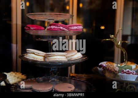 Macaron colorati su un banco di vetro in una pasticceria, deliziosi pasticcini e vari dessert Foto Stock