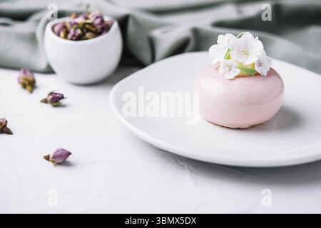 Natura morta alimentare, mousse rosa decorata con fiori bianchi Foto Stock