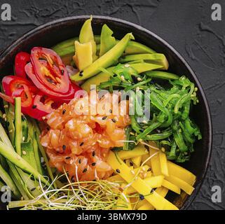 Cibo natura morta, ciotola di salmone hawaiano con alghe, avocado, semi di sesamo e cetriolo Foto Stock