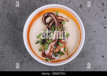 Natura morta alimentare, polpo alla griglia con zuppa di crema di patate Foto Stock