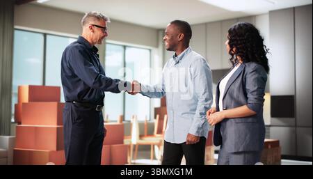 Consulente immobiliare che dà la mano a coppie di famiglie multirazziali che festeggiano Foto Stock