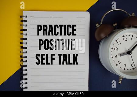 Esercitarsi con il testo di autocomunicazione positivo scritto sul blocco note con sveglia su sfondo giallo Foto Stock