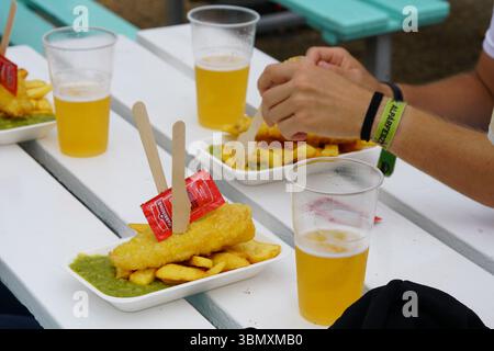 Pasto a base di pesce e patatine fritte nel patio all'aperto con bicchieri di birra fredda. Brighton, Inghilterra Foto Stock