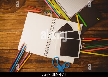 Il design piatto mostra un notebook a spirale su una scrivania in legno con matite colorate, pastelli e forbici Foto Stock