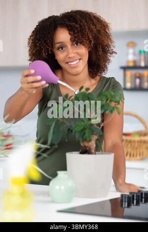una donna felice spruzza acqua sull'albero del bonsai Foto Stock