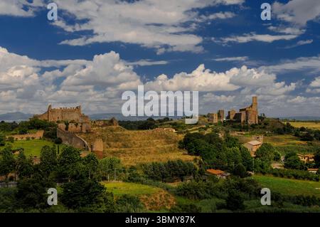 La lunga storia di Tuscania nella provincia di Viterbo, Lazio, Italia, si sviluppa su colline adiacenti: Un castello medievale in rovina su un'antica acropoli etrusca terrazzata o cittadella (a sinistra), rovine romane, mura cittadine, torri di difesa e due basiliche romaniche (a destra) che fungevano in sequenza da cattedrale della città. Foto Stock