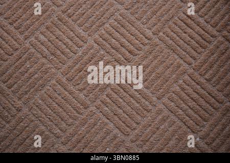 Sfondi con filettatura sintetica. Tappeto strutturato in tessuto marrone con motivo lineare e setole per porte d'ingresso. Foto Stock