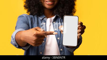 Donna nera che punta allo smartphone con schermo vuoto Foto Stock