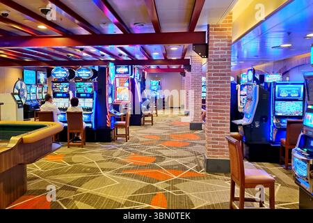 Casinò all'interno della lussuosa nave da crociera Emerald Princess con file di slot machine che illuminano uno spazio con luci blu e rosse. Foto Stock