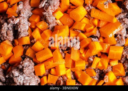 Il manzo macinato con carote, cipolle e sedano viene fritto per preparare una salsa alla bolognese secondo una tradizionale ricetta italiana. Sfondo. Vista dall'alto. Foto Stock