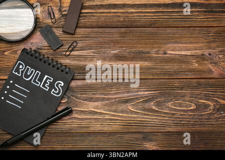 Quaderno con elenco vuoto di regole e cancelleria su sfondo in legno Foto Stock