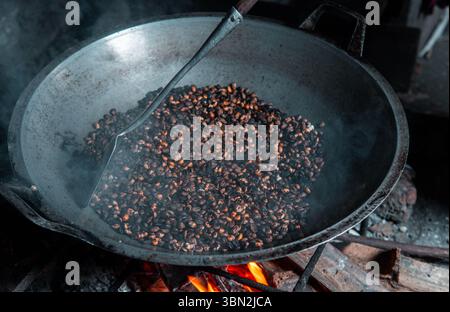 Tradizionale tostatura di chicchi di caffè mescolati con mais su stufa a legna. Una tecnica locale per creare un gusto distinto, catturato in un villaggio rustico. Foto Stock