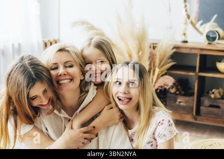 Mamma e figlie si stanno divertendo e ingannando intorno ad abbracciarsi e ridere Foto Stock