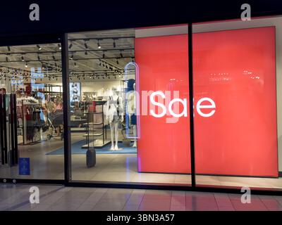 Insegna di vendita gigante visualizzata sul muro rosso dietro le vetrine del negozio Nike Sports Fashion Store di Londra, Regno Unito Foto Stock