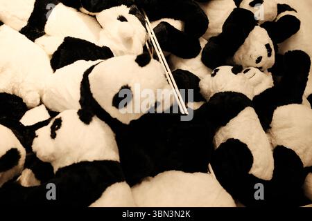 Una grande pila di peluche di panda bianchi e neri riempie un cestino in un negozio di giocattoli. Morbido e affascinante, ideale per i bambini Foto Stock