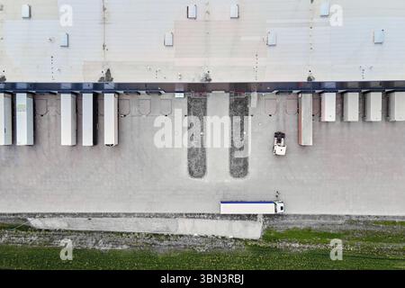 Vista aerea delle piattaforme di carico del magazzino con rimorchi parcheggiati e autocarri in funzione. Infrastruttura logistica moderna Foto Stock