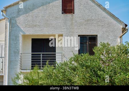 Vecchio muro con persiane in legno scuro su casa residenziale bianca. Esterno di una casa mediterranea Foto Stock
