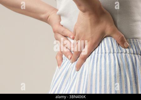 Giovane donna che soffre di dolore alla schiena o ai reni, fotografia in studio Foto Stock