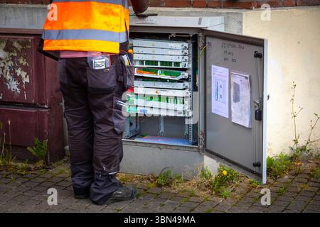 Lavoratore che lavora su un armadio stradale in fibra ottica, un telaio di distribuzione in fibra ottica o un SRO in fibra ottica (per un sub-distributore ottico) Foto Stock