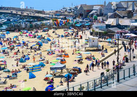 Lyme Regis, Dorset, Regno Unito. 30 giugno 2025. Meteo nel Regno Unito. I bagnanti affollarono la spiaggia affollata presso la località balneare di Lyme Regis per crogiolarsi al caldo sole nel giorno più caldo dell'anno finora. Le temperature sono destinate a salire bene a metà degli anni '30, mentre l'ondata di calore di giugno persiste. Crediti: Celia McMahon/Alamy Live News Foto Stock