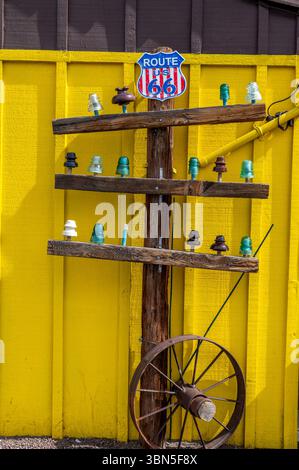 Mostra vintage Route 66 con isolanti in vetro colorato e ruota per carri su una parete in legno giallo brillante a Seligman, Arizona, che simboleggia l'americana Foto Stock