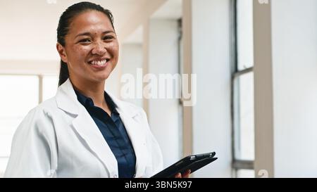 Professionista sanitario femminile fiducioso sorridere in Ufficio medico con un tablet Foto Stock