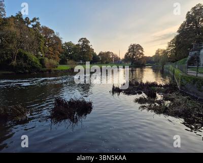 Tranquillo paesaggio fluviale al tramonto con alberi autunnali e riflessi sull'acqua vicino al castello di Warwick nel Warwickshire, Inghilterra. Foto Stock
