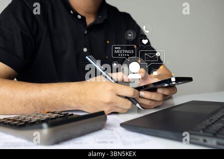 Uomo d'affari che utilizza lo smartphone con icone fluttuanti di chat, posta, riunioni e comunicazione su uno spazio di lavoro digitale. Foto Stock