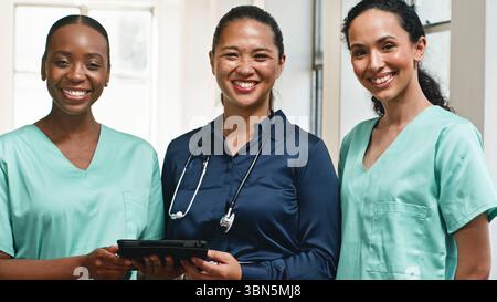 Team medico diversificato di professionisti sorridenti e in posa in un ambiente di lavoro ben illuminato Foto Stock