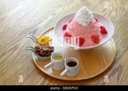 Ghiaccio fruttato rasato di fragole rosse o bingsu su una ciotola bianca con condimenti, salsa e marmellata. Foto Stock
