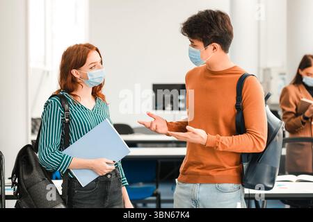 Studenti internazionali che indossano maschere mediche e parlano Foto Stock
