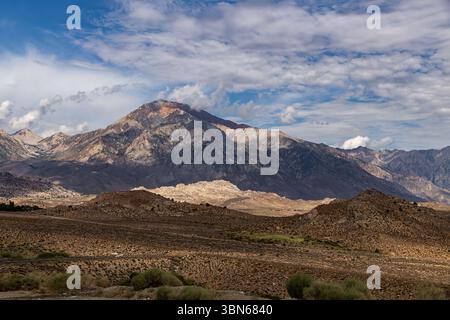 Il monte Tom torreggia sui massi Buttermilk con nuvole soffici su un cielo blu. Foto Stock