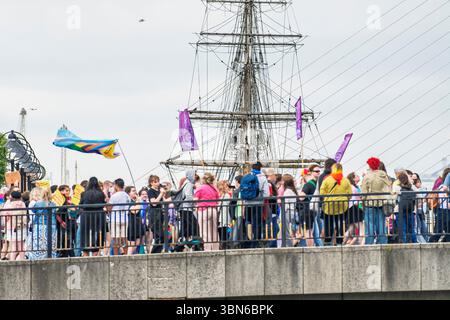 Un Pride Marchers in vibranti colori arcobaleno al ponte Talbot di fronte al veliero Jeanie Johnston. 28 giugno 2025 Foto Stock