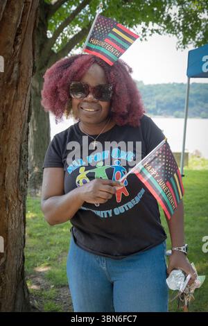 Una donna che regge e indossa bandiere di buon Juneteenth durante una festa al Waryas Park, Poughkeepsie, nella contea di Dutchess, New York. Foto Stock