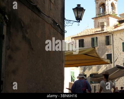 Gli esploratori passeggiano per le strette strade della città vecchia di Cattaro, ammirando l'architettura storica e godendosi l'atmosfera vivace al sole. Foto Stock