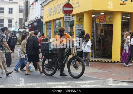Un corriere fast food con il viso coperto da una maschera a Brighton, Regno Unito Foto Stock