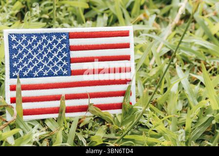 Bandiera USA ricamata ecologica sull'erba con luce naturale calda, simbolo della sostenibilità e della consapevolezza del clima in Nord America. Foto Stock