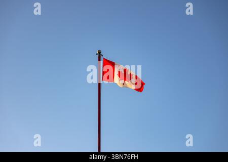 Bandiera del Canada che segnala in una resistenza con cielo blu sullo sfondo Foto Stock