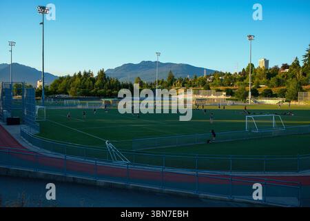 Pista e campi da calcio all'Empire Field presso l'Hastings Park a East Vancouver, British Columbia, con le montagne della North Shore alle spalle. Foto Stock