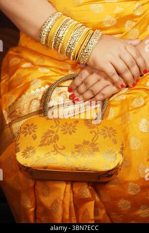 Donna elegante con un abbigliamento giallo che regge una borsa elegante Foto Stock