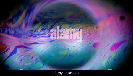 Fluido defocalizzato a benzina. Pittura mistica. Sfera colorata di miscela di olio a emulsione leggera. Sfondo cosmico blu viola cornice al neon con spazio nero. Foto Stock