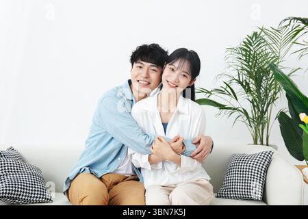 Una giovane coppia si abbraccia sul divano Foto Stock