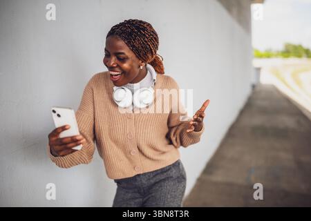 Ritratto di una giovane donna nera che sta effettuando una videochiamata sullo smartphone. Foto Stock