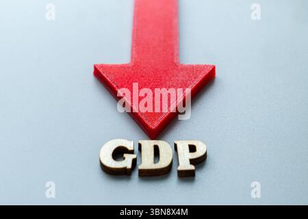 Una freccia rossa è rivolta verso il basso, con lettere in legno che indicano "PIL". Declino del prodotto interno lordo, contrazione economica, recessione Foto Stock