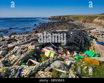 Plastica e funi gettate gettano via una spiaggia rocciosa a Unst, Shetland, mettendo in evidenza l'inquinamento ambientale Foto Stock